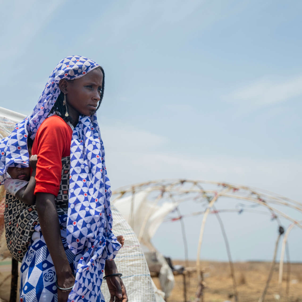 En mamma bär sitt barn på ryggen.