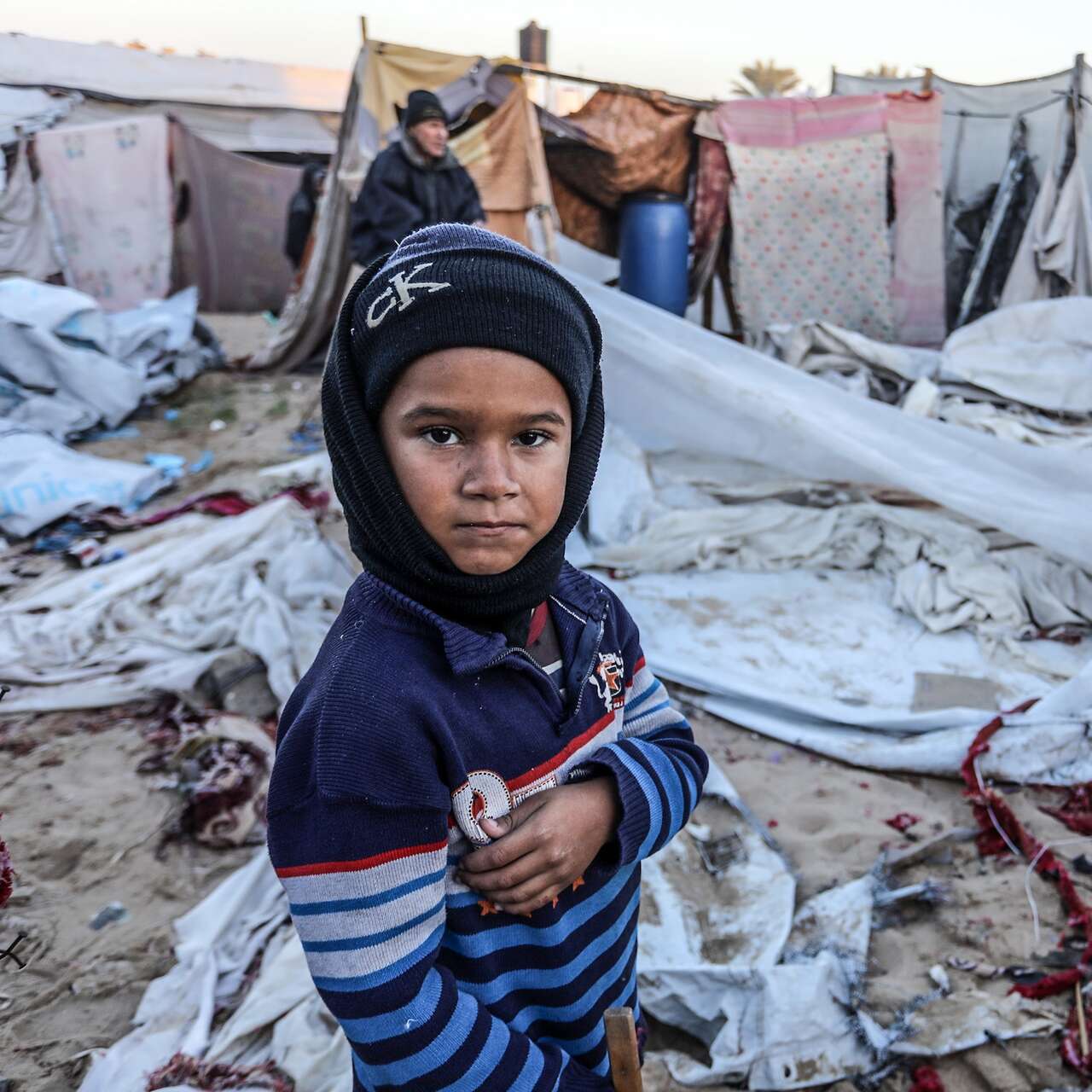 한 가자 어린이가 폐허 앞에서 카메라를 바라보고 있습니다.