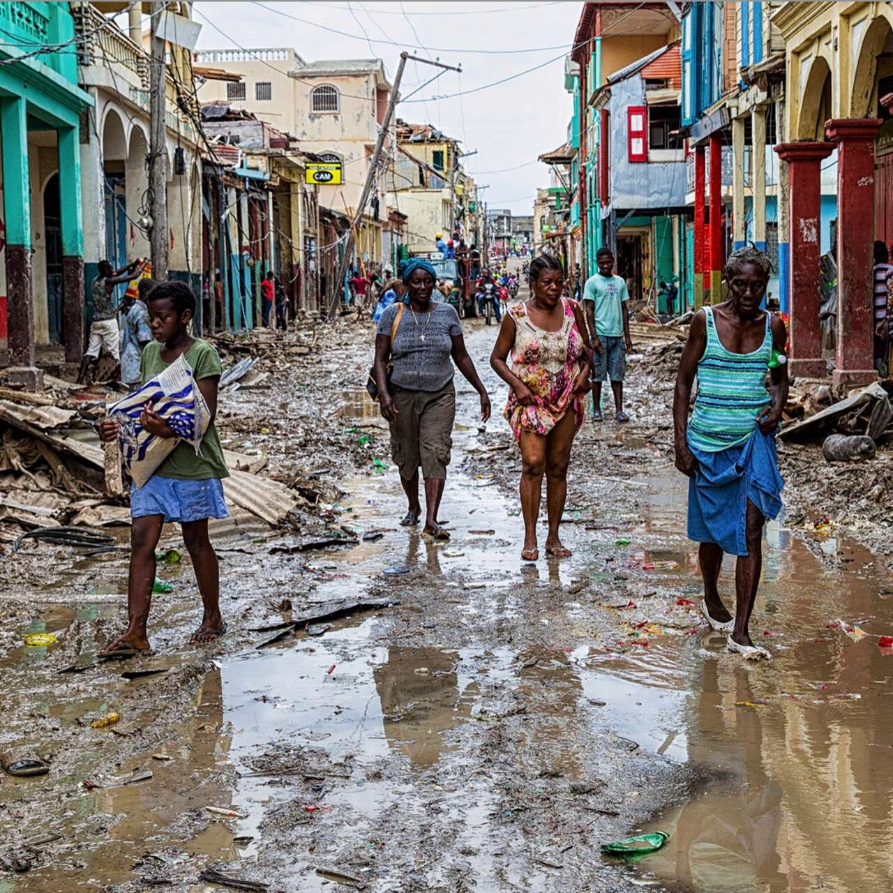 Four Haitians walked through a muddied, destroyed street.