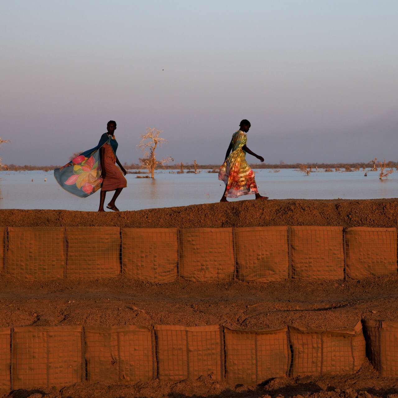 Two women walk near a flooded field in South Sudan.