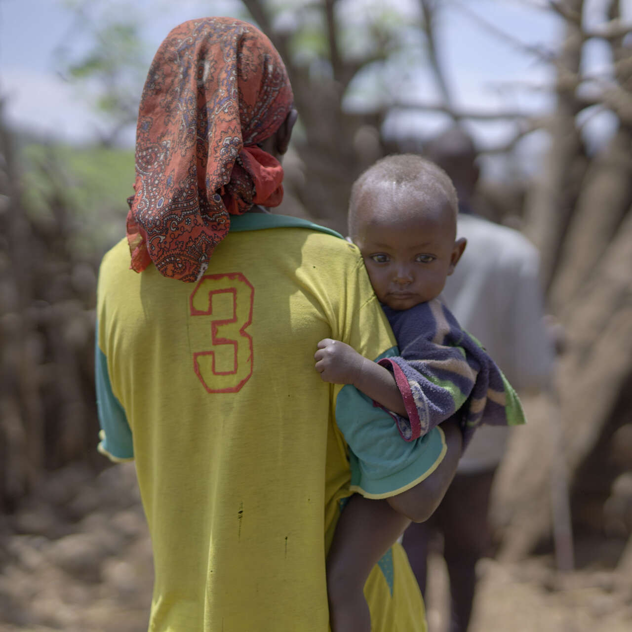 한 에티오피아 어린이가 엄마 품에 안겨 바라보고 있습니다.