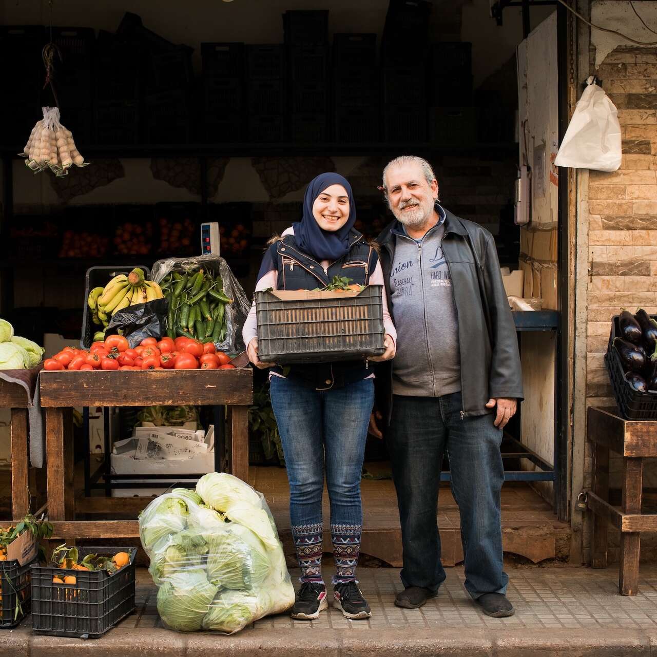 알라가 아빠와 함께 자신의 사업장 앞에서 웃고 있습니다