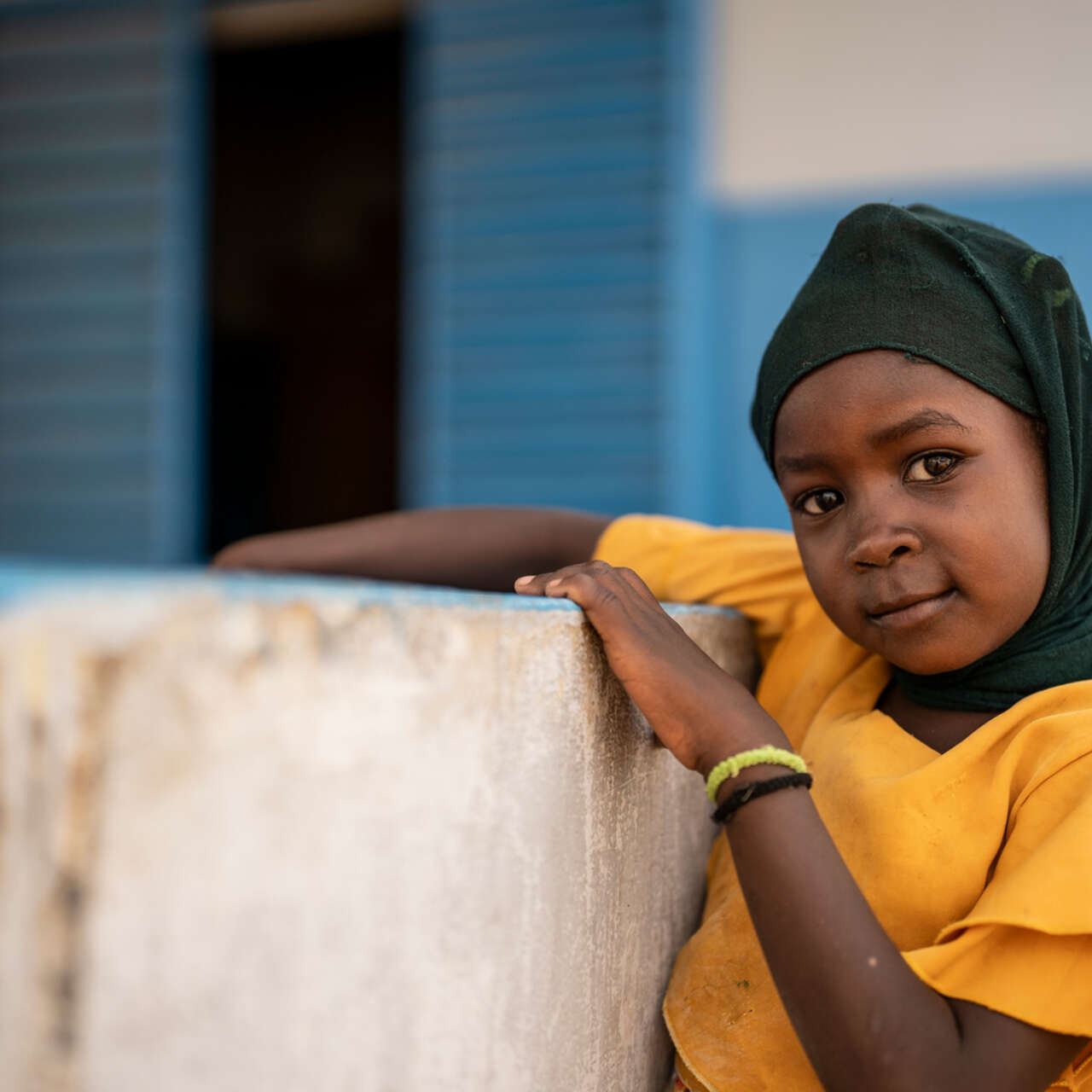 En flicka lutar sig mot en betongmur. 