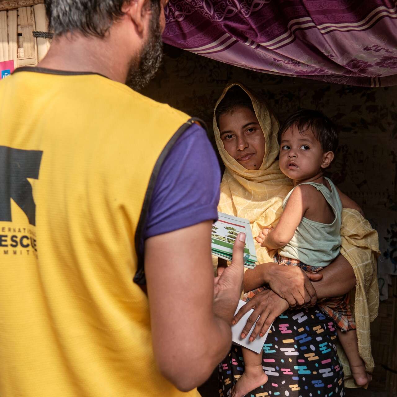 An IRC staff member speaks to a refugee and her child in Cox's Bazaar, Bangladesh.