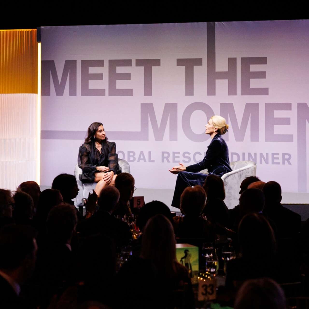 Two people sit on stage and engage in a conversation at the IRC's Global Rescue Dinner.