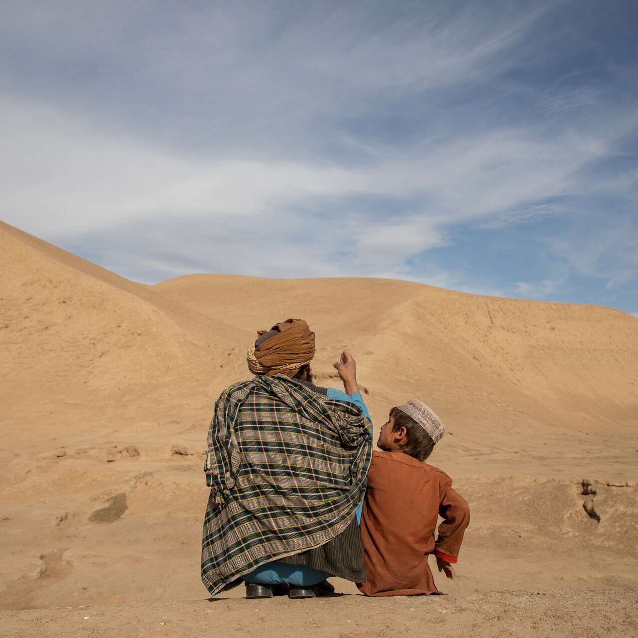 Abdul Haq outside with his oldest son Naqib Ullah as they talk about their village mountains in Afghanistan.
