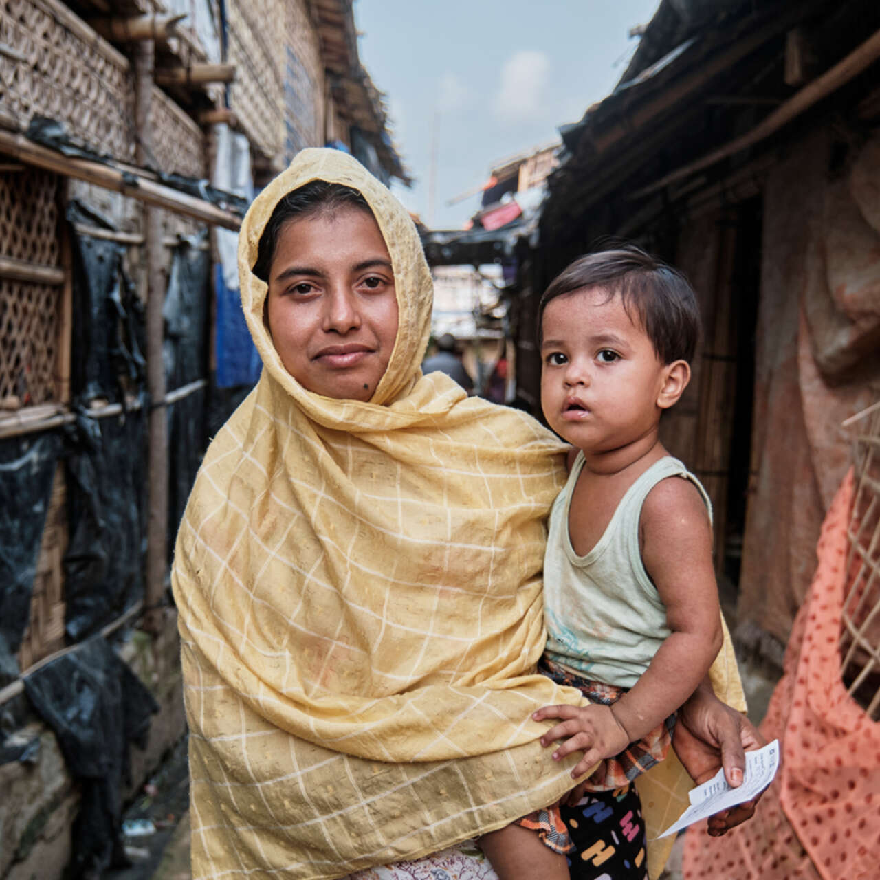  Fatema står bärandes med hennes tvååriga dotter Hajera Bibi.