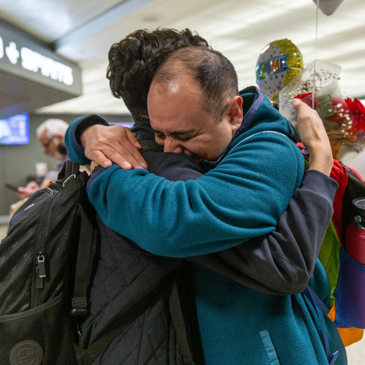 Two men hugging while having a reunification at the airport. 