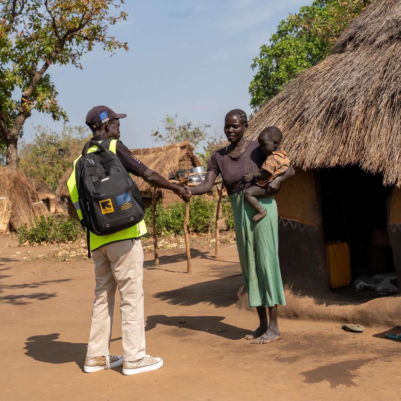 Martin greets Elizabeth, who is holding her young child during a home visit. For many families in the settlement, a knock at the door from Martin is the first step toward getting care.