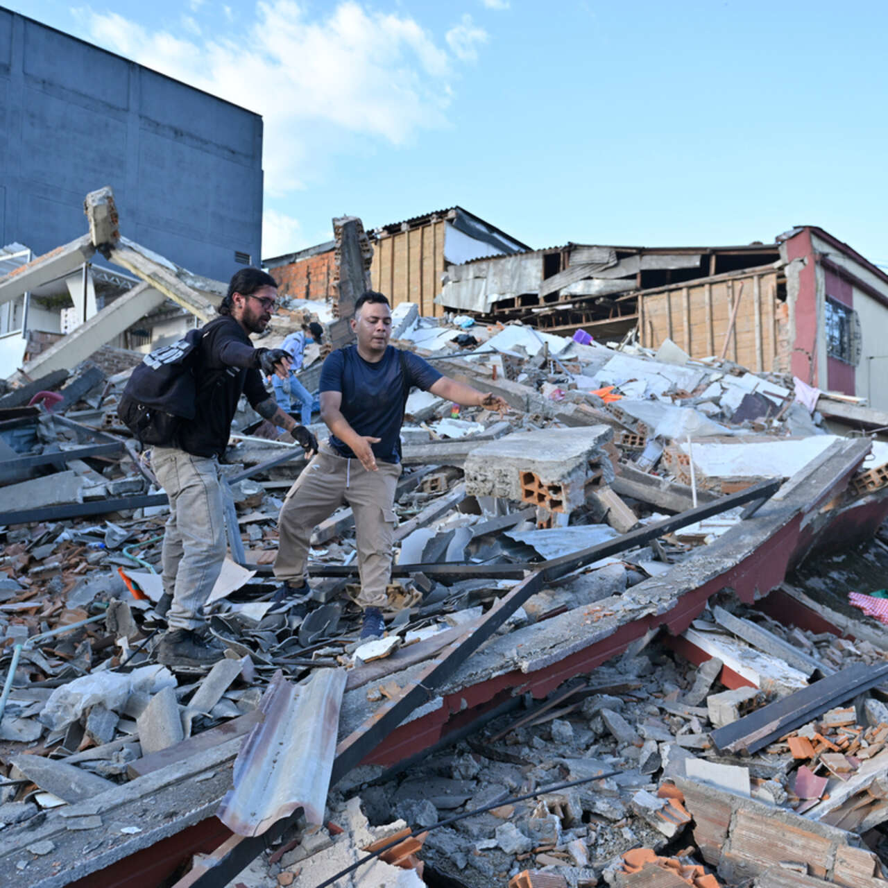 People and rescuers search for victims amid debris of a collapsed building at the city center after a magnitude 7.4 earthquake struck Colombia. 