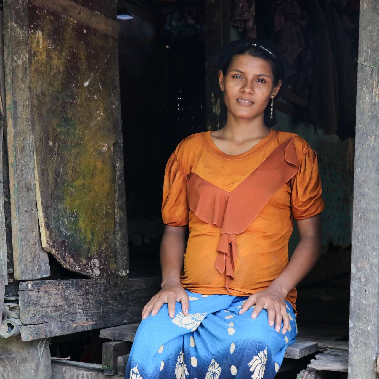 A woman sits on the steps of her home in Myanmar as her portrait is taken.