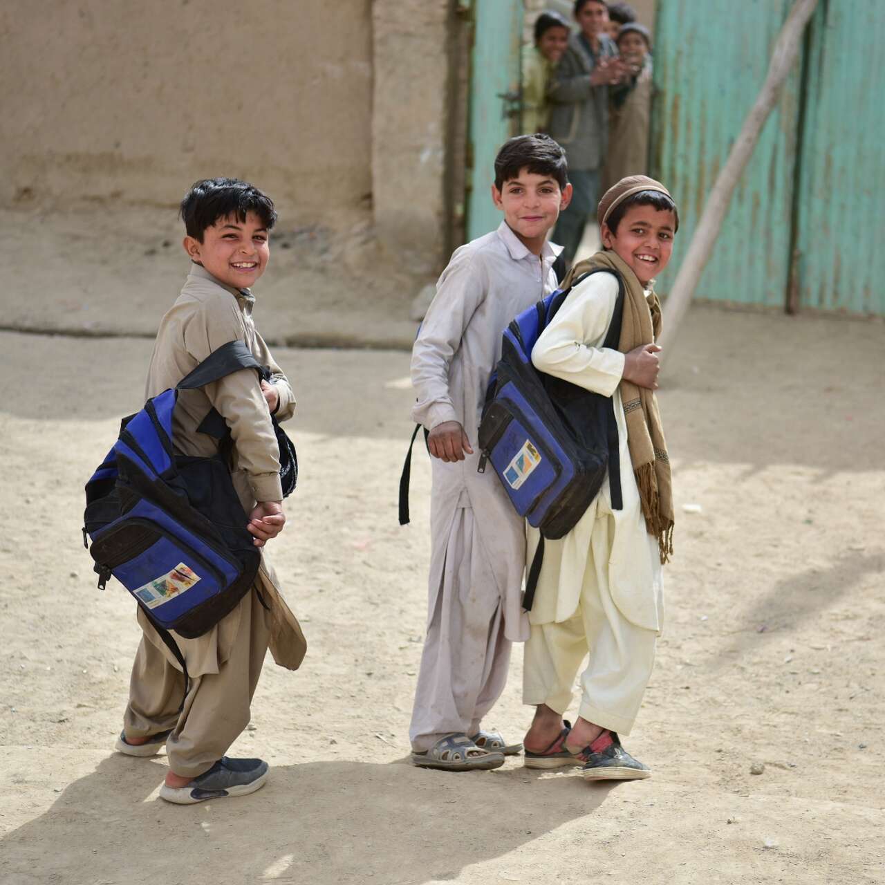 Three boys walk through a school yard in Pakistan.