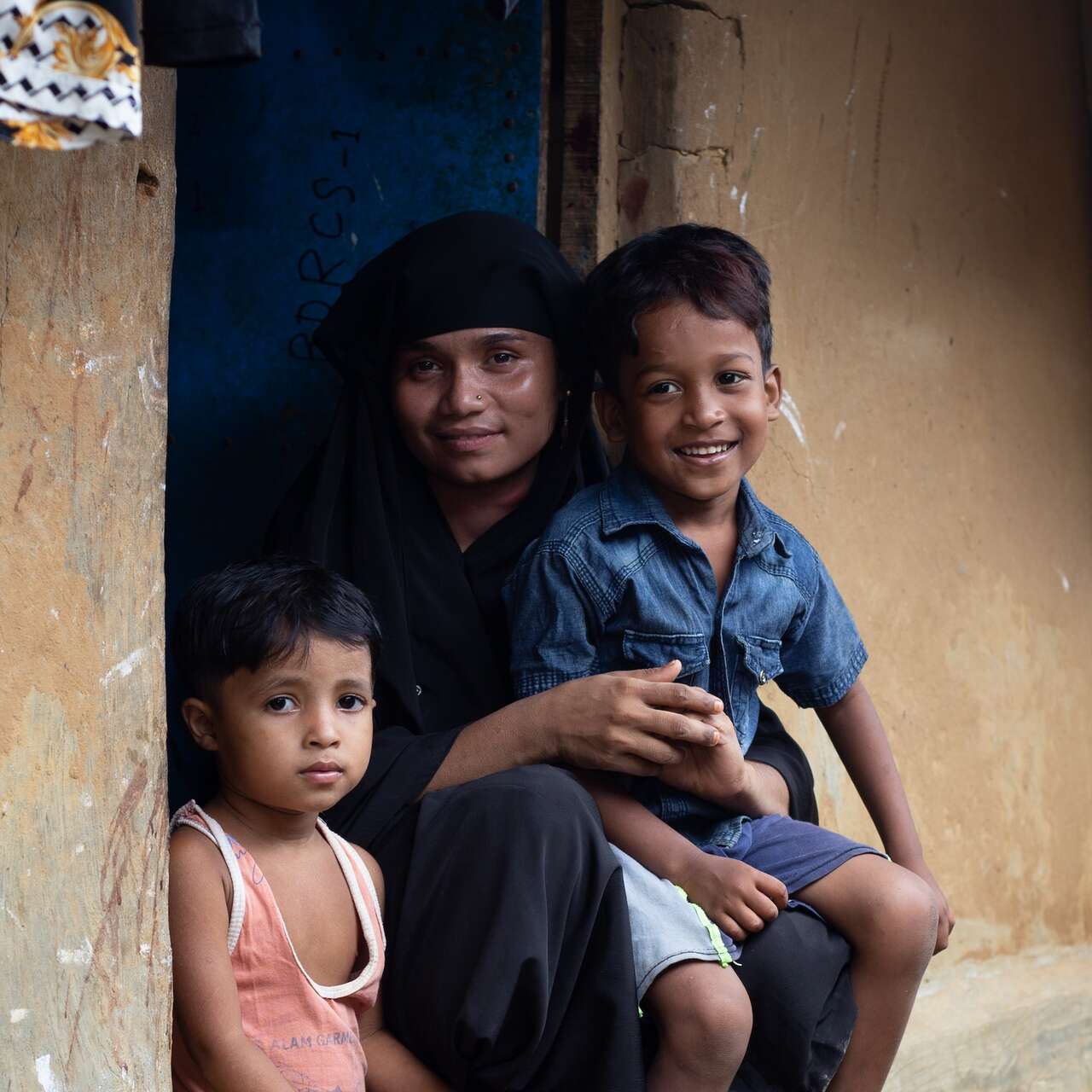 A mother sitting with her two sons on a stoop