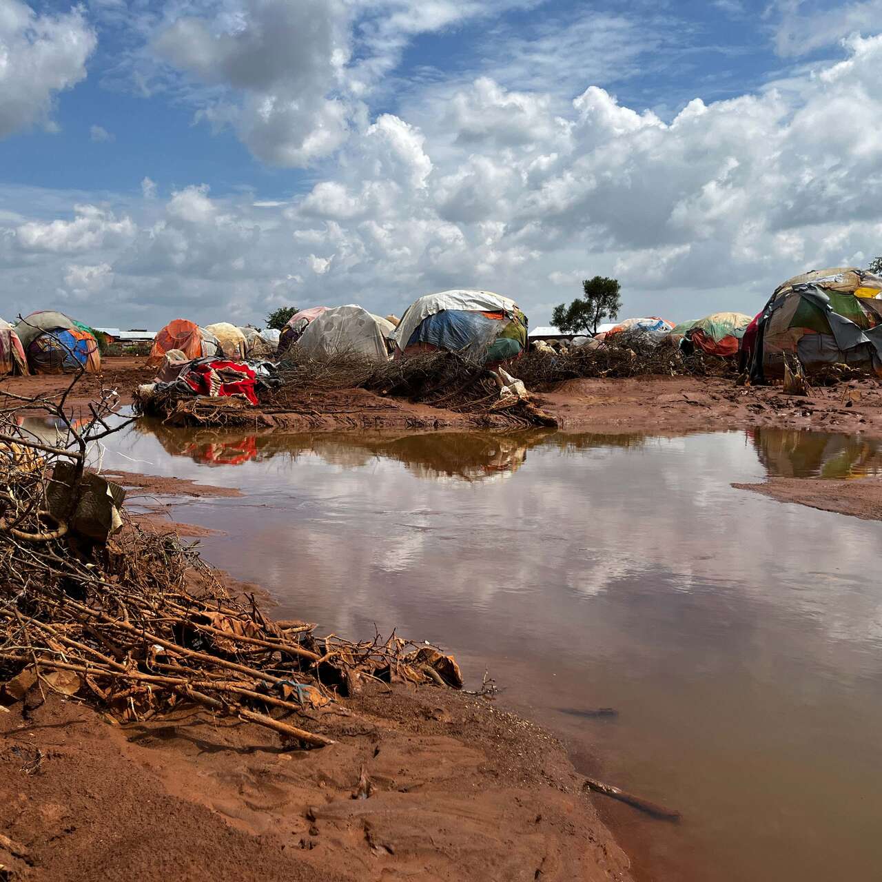 A group of shelters lie near a flooded path.