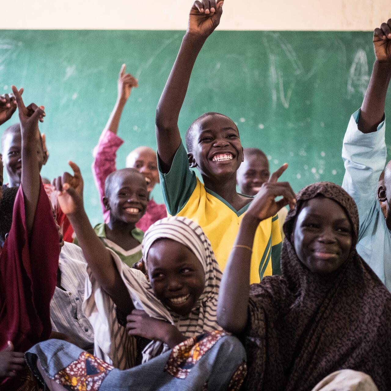 Students excitedly raise their hands in class at an International Rescue Committee supported school in Nigeria.