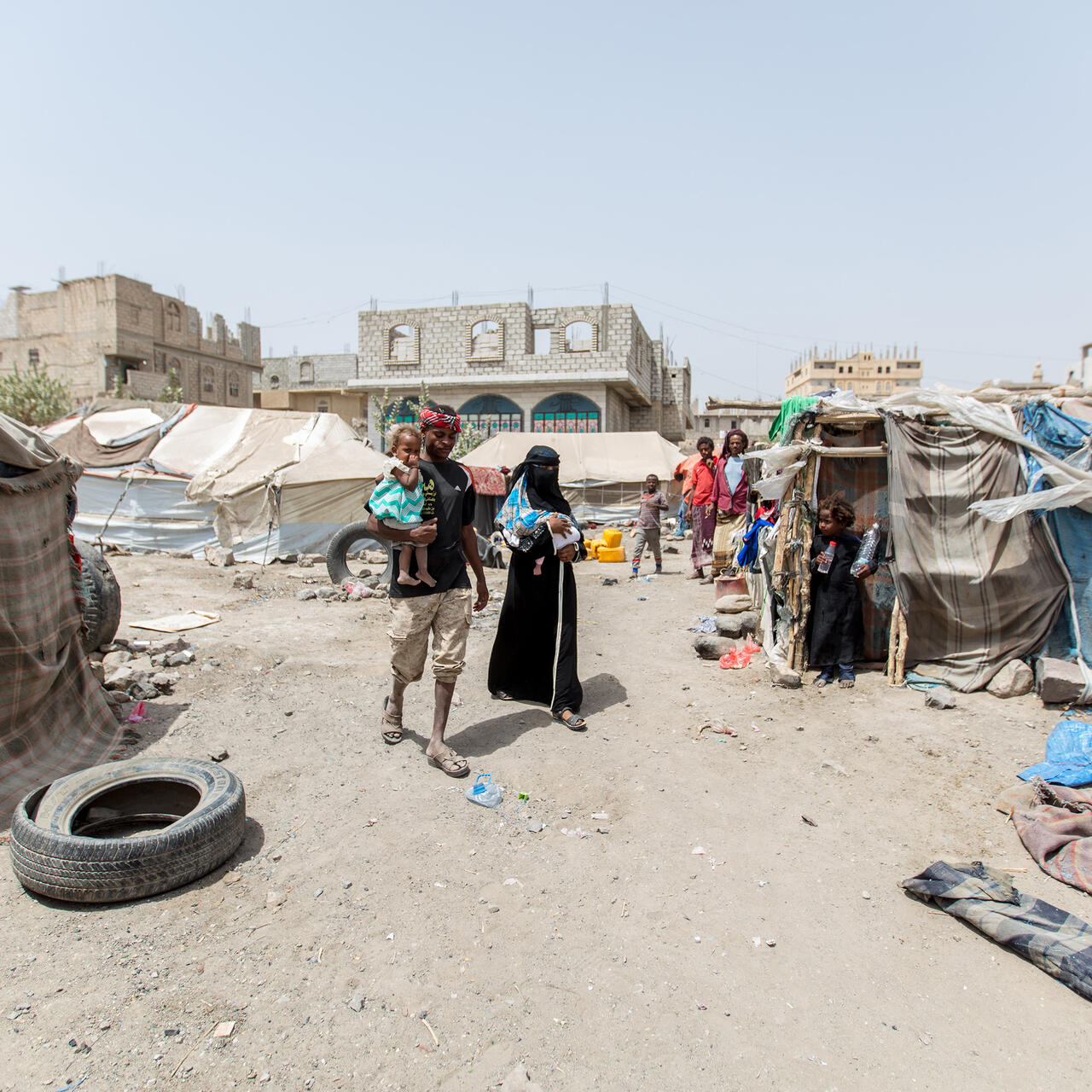 A family walk through a camp in Yemen.