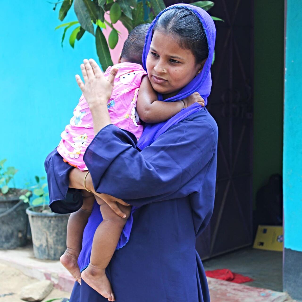 Lovely Akter holds her nine-month-old daugher