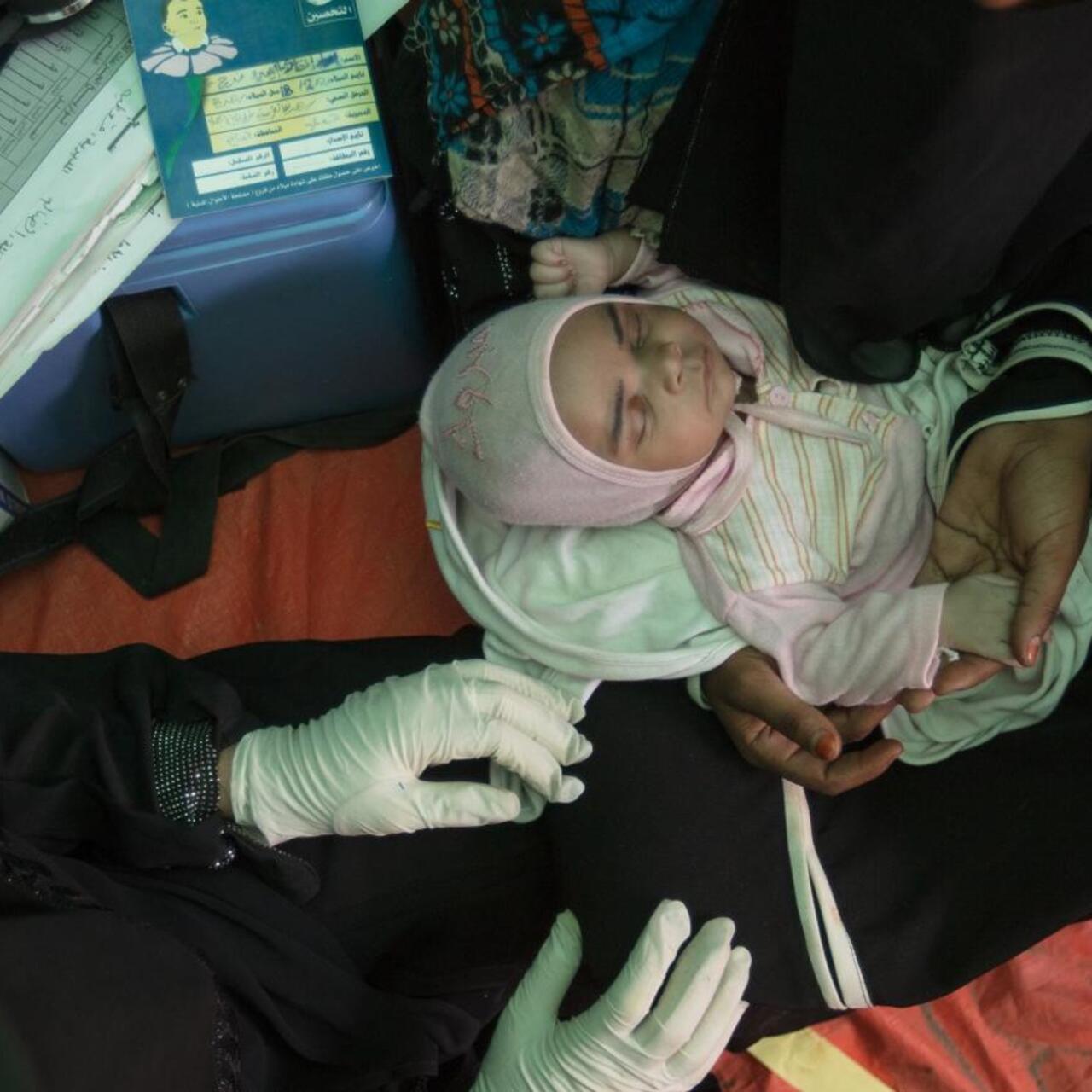 Bodo sits in a tent holding her baby, who she named Enqath or "Rescue" after the International Rescue Committee.