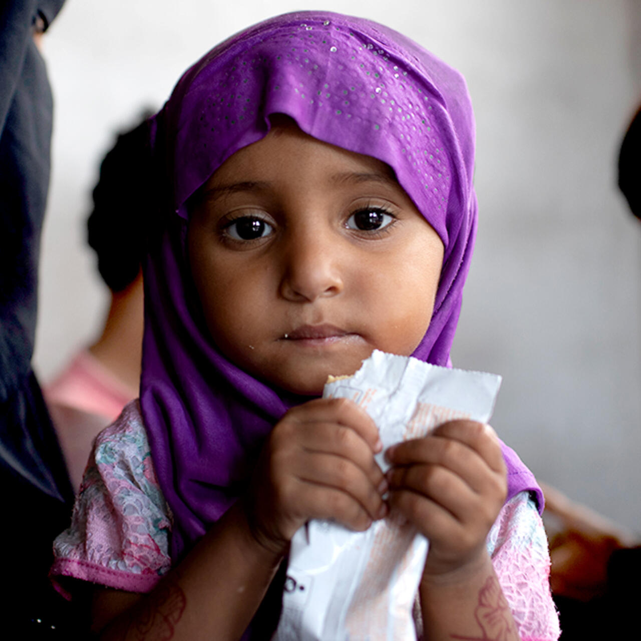 In Yemen, a young girl being treated for acute malnutrition eats Plumpy'nut, a peanut butter based nutritional paste, from a packet.
