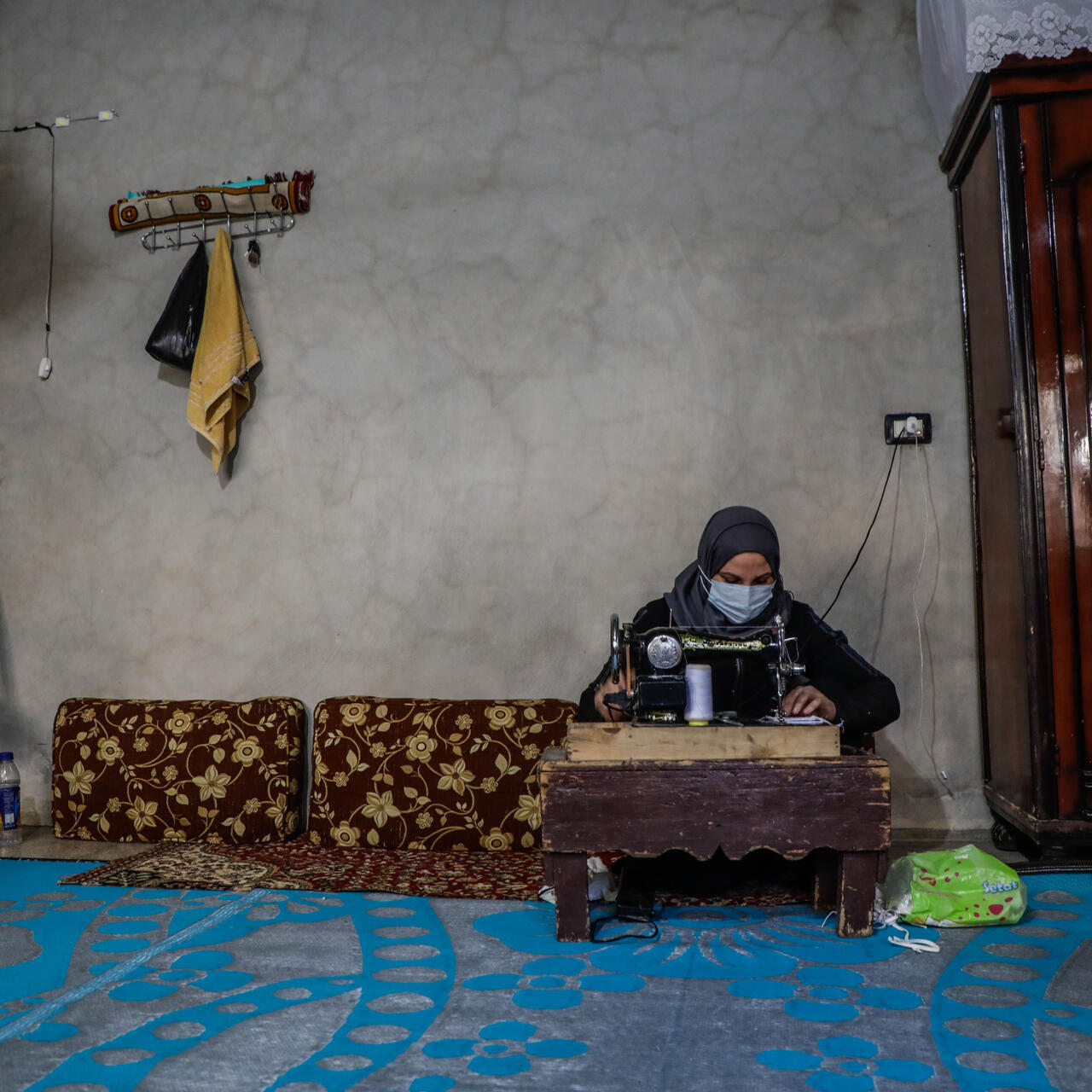 Um Abdo works at her sewing machine making COVID-19 face masks
