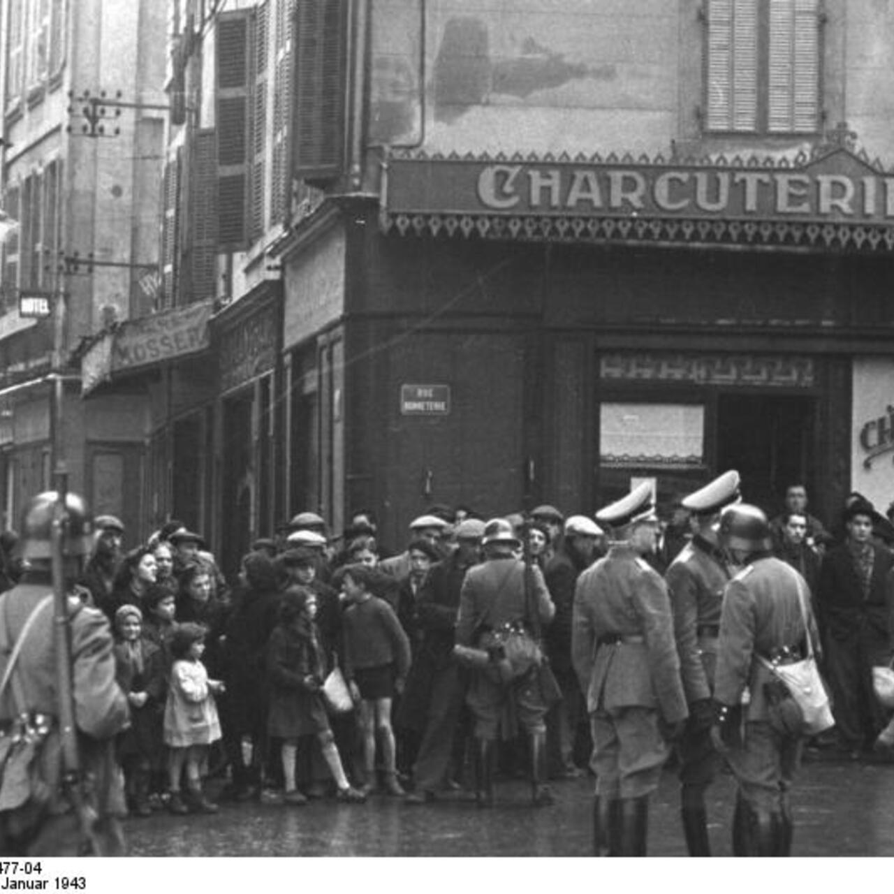 People are rounded up by Nazi forces outside a butcher shop in Marseilles, France