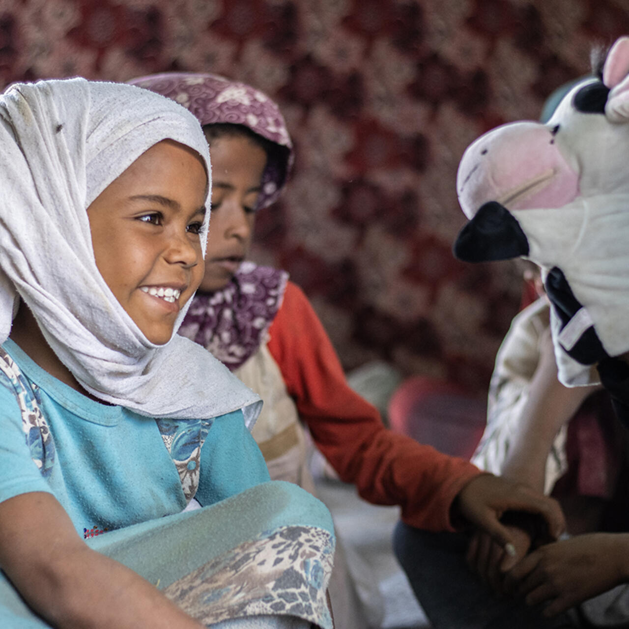 Young girl smiles at a cow puppet