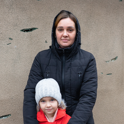 A mother is standing with her daughter in their home yard in Kherson region, Ukraine.