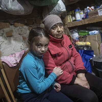 A young girl sits with a family member in a shelter in Lyman, Ukraine, after the Ukrainian army retook control.