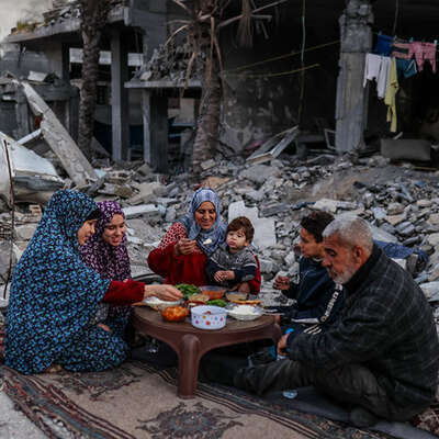  A Palestinian family breaking their fast and eating an iftar meal among the rubble of their destroyed house.