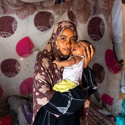 A mother holds her daughter in Al-Dhale’e, Yemen