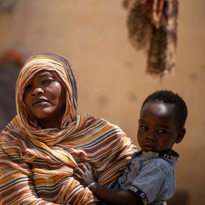 A Sudanese mother holds a young child close in her arms.