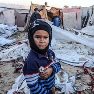 En pojke i Gaza står vid förstörda tält mitt i vintern. RESCUE finns på plats med stöd.