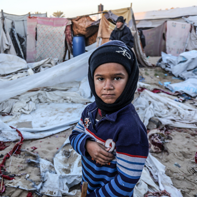 En pojke i Gaza står vid förstörda tält mitt i vintern. RESCUE finns på plats med stöd.