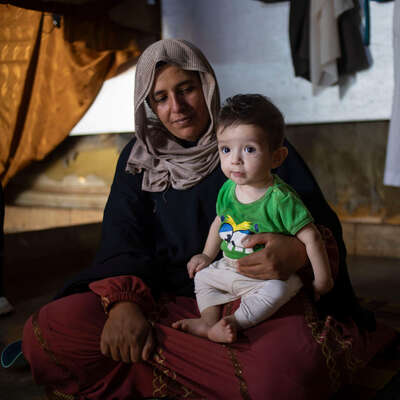 A Lebanese mum cradles her infant on the ground in southern Beirut after being displaced by airstrikes.