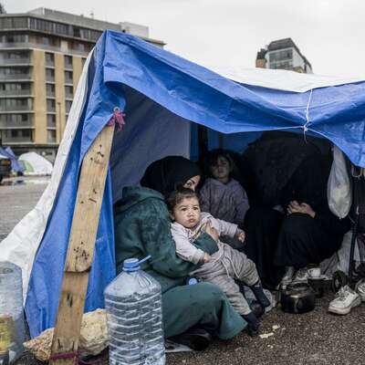 A mother holds a child in a green tent in Beirut, Lebanon