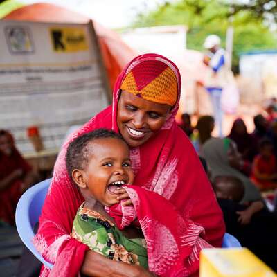 A Somali mother sits with her children at an IRC-supported health facility, where her children get a health check.