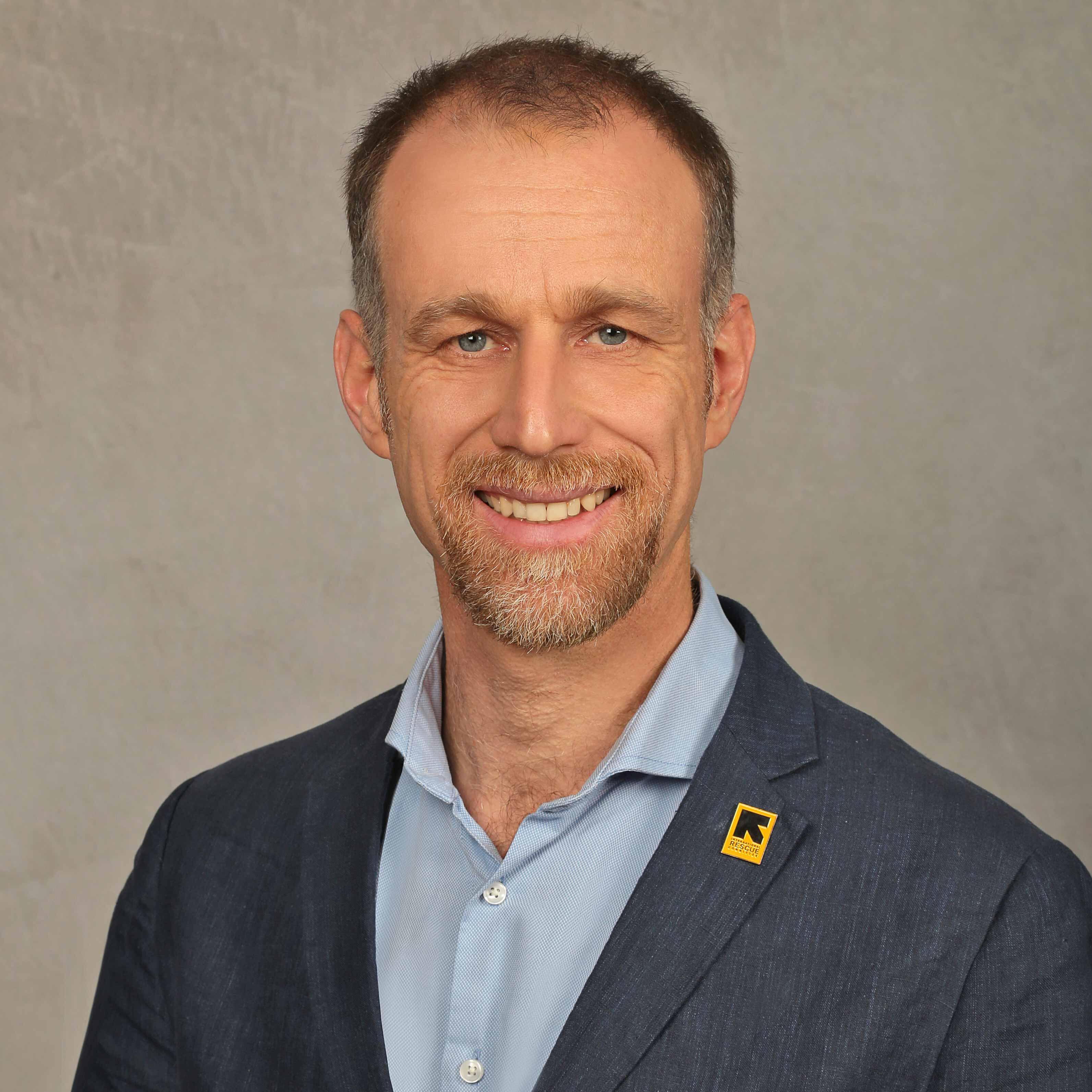 Portraitfoto von IRC Deutschland Geschäftsführer Ralph Achenbach mit IRC-Pin lächelt in die Kamera