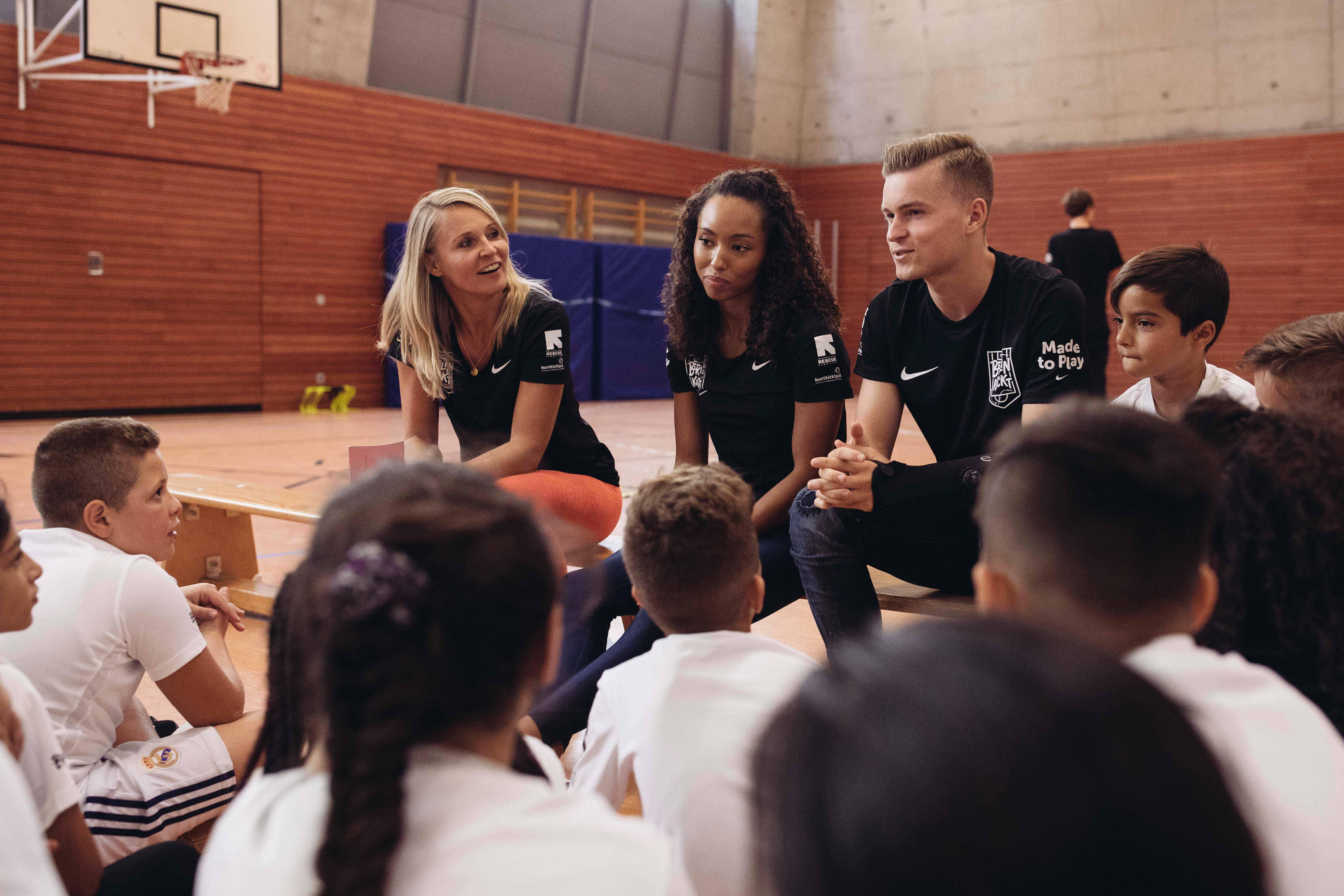 Schüler*innen, die am Berlin Kickt Programm von International Rescue Committee teilnehmen bei einer Trainingseinheit mit den Spitzensportlern Jacqueline Otchere (o.M.) und Maximilian Mittelstädt