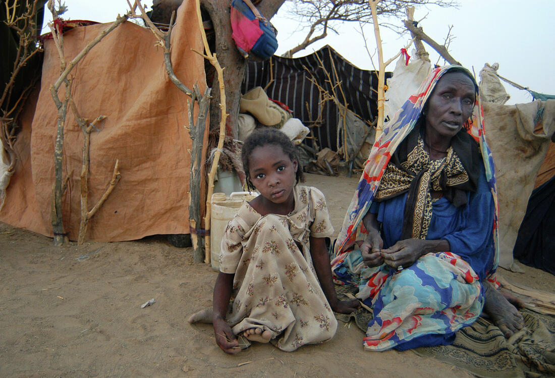 Ein Mädchen und eine Frau sitzen in Bahai, Tschad auf dem Boden