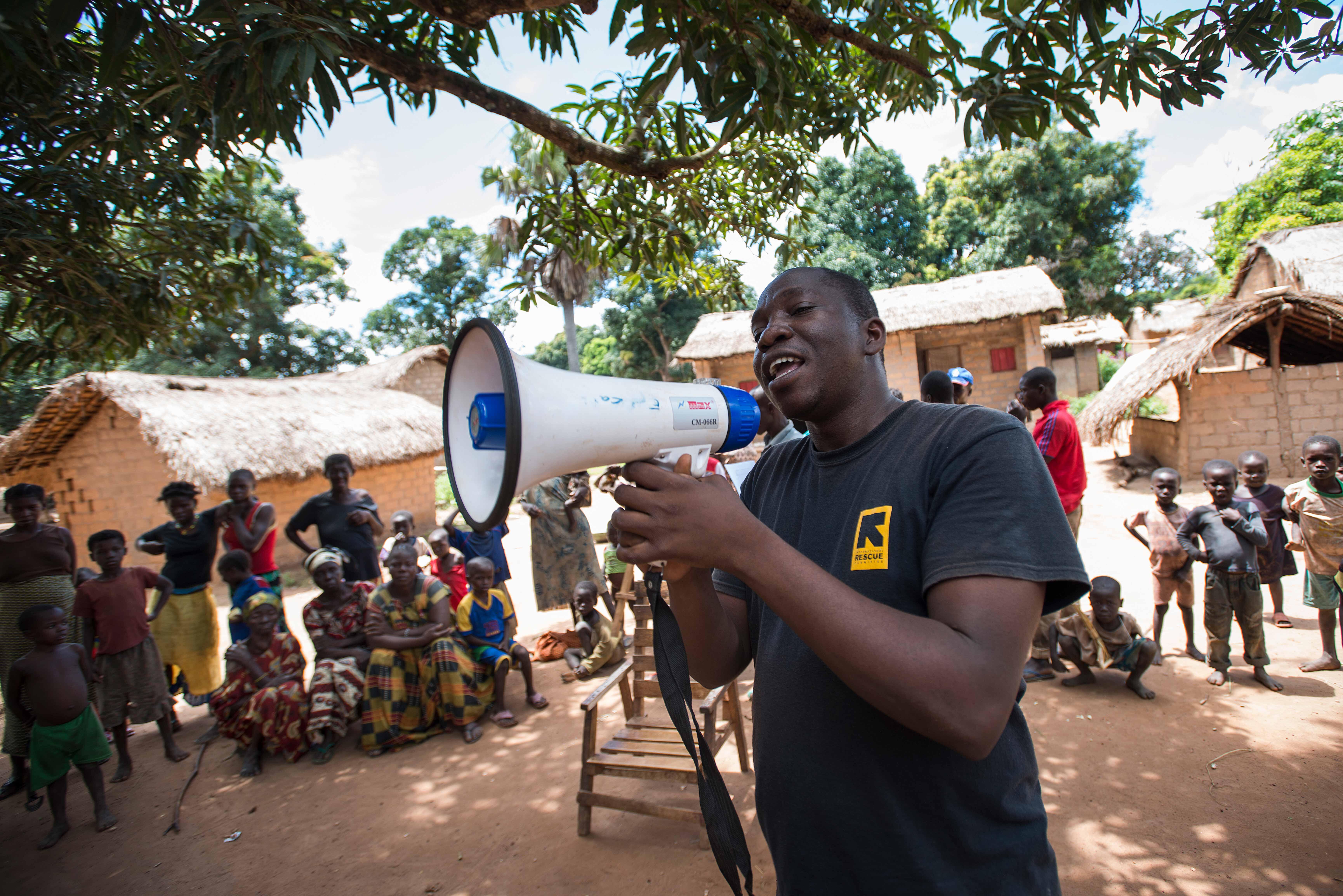 A man shouts to people surrounding him with a megaphone