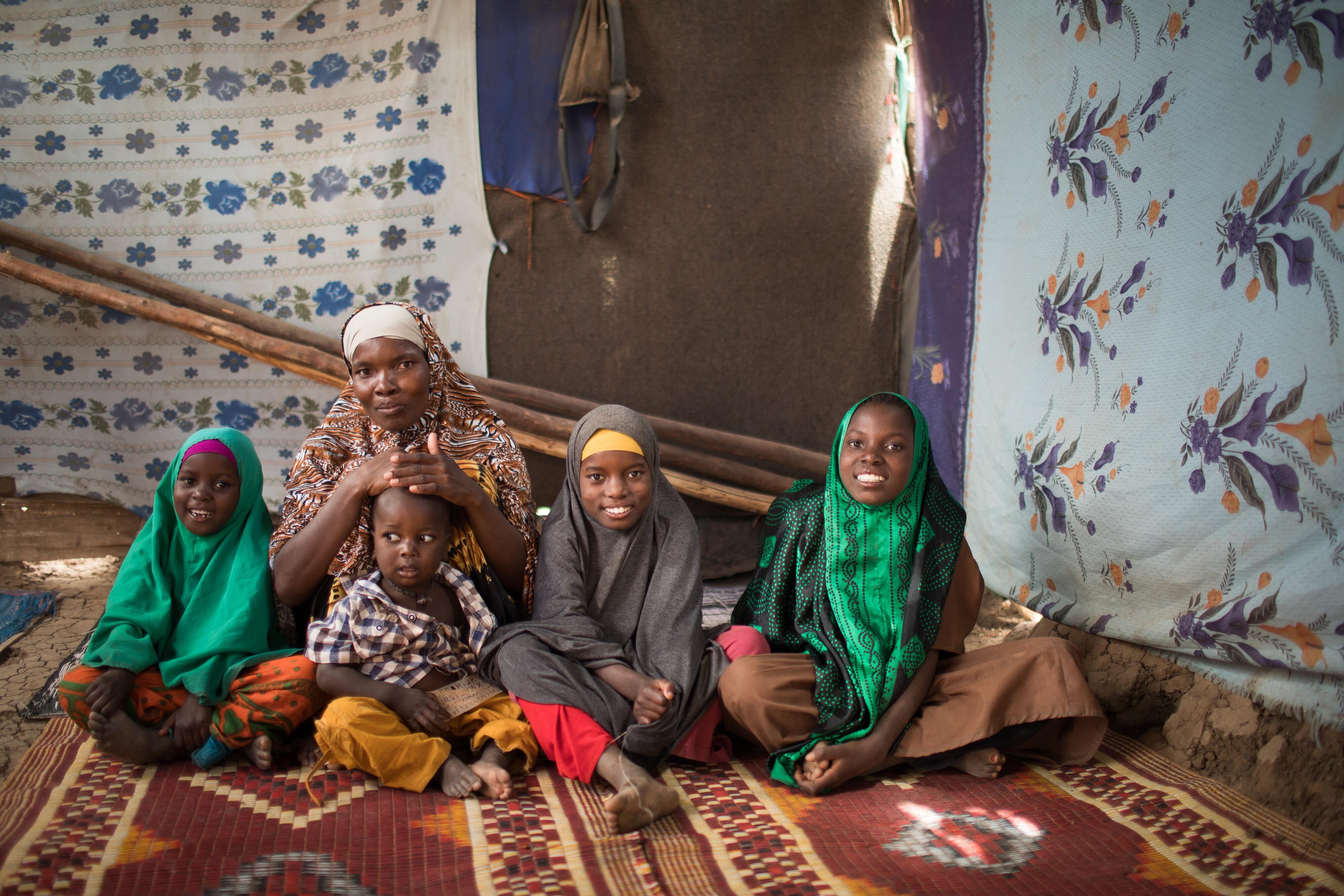 A mother with her four children sitting on a carpet