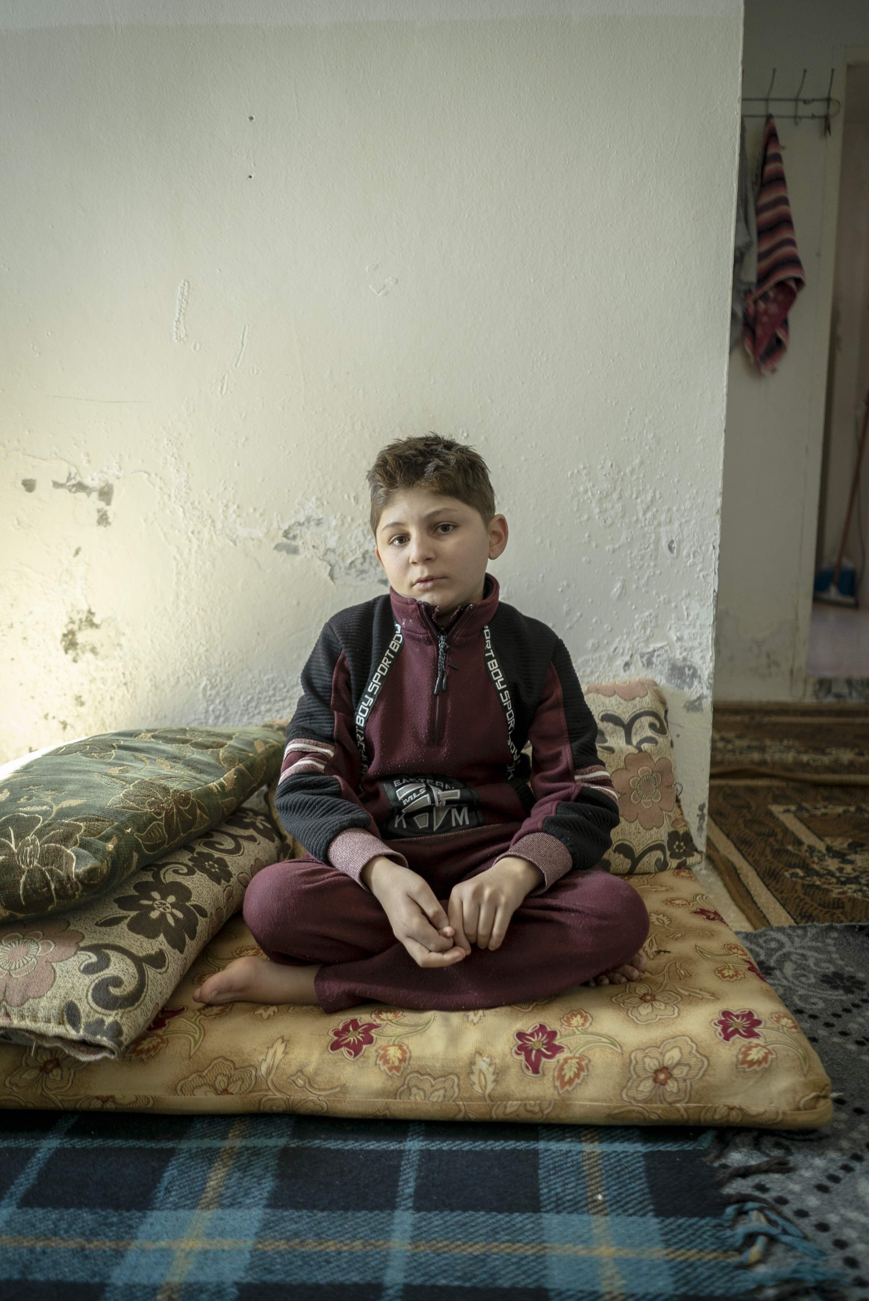 A boy sitting on a matress on the floor