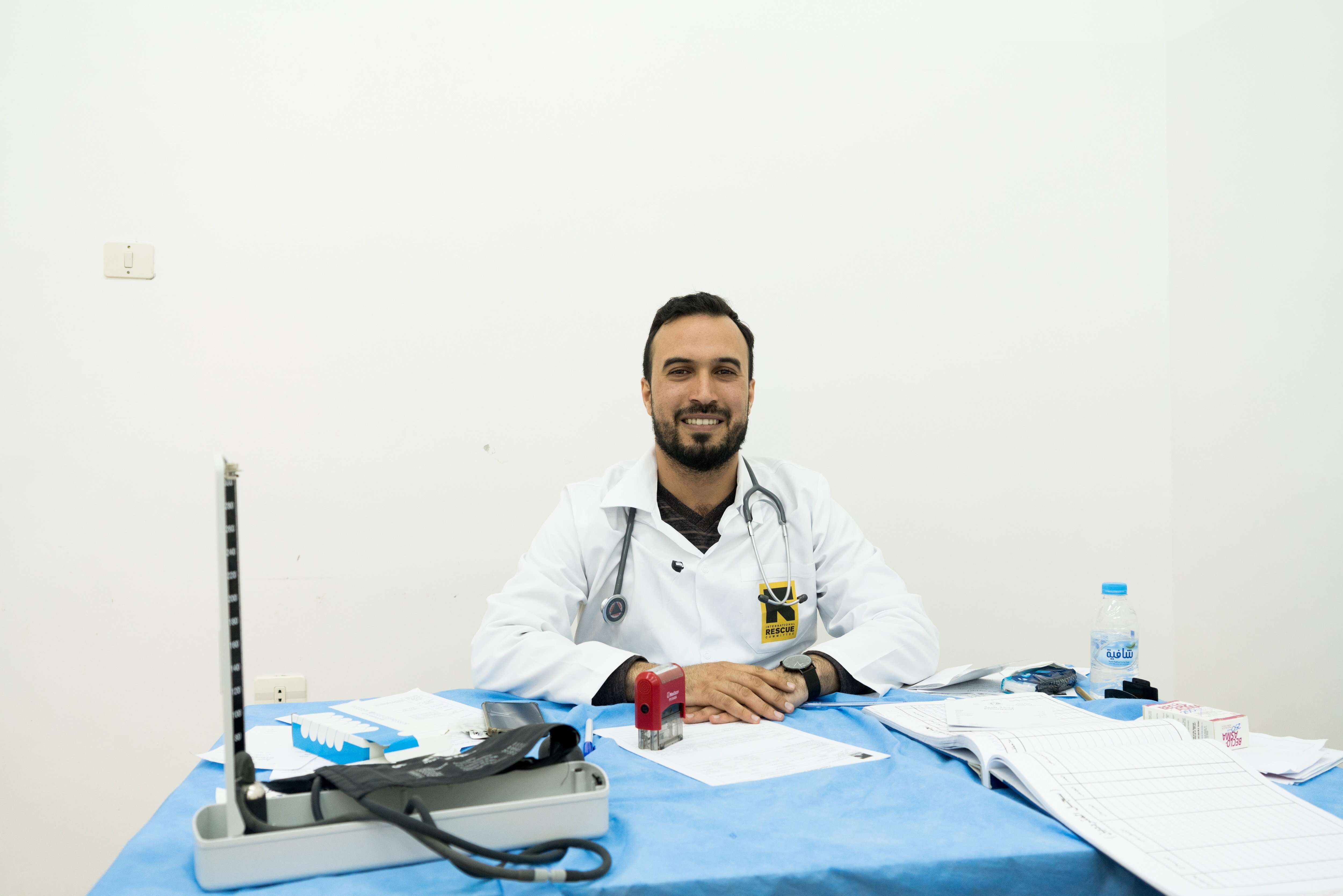 A man sits smilingly behind a desk