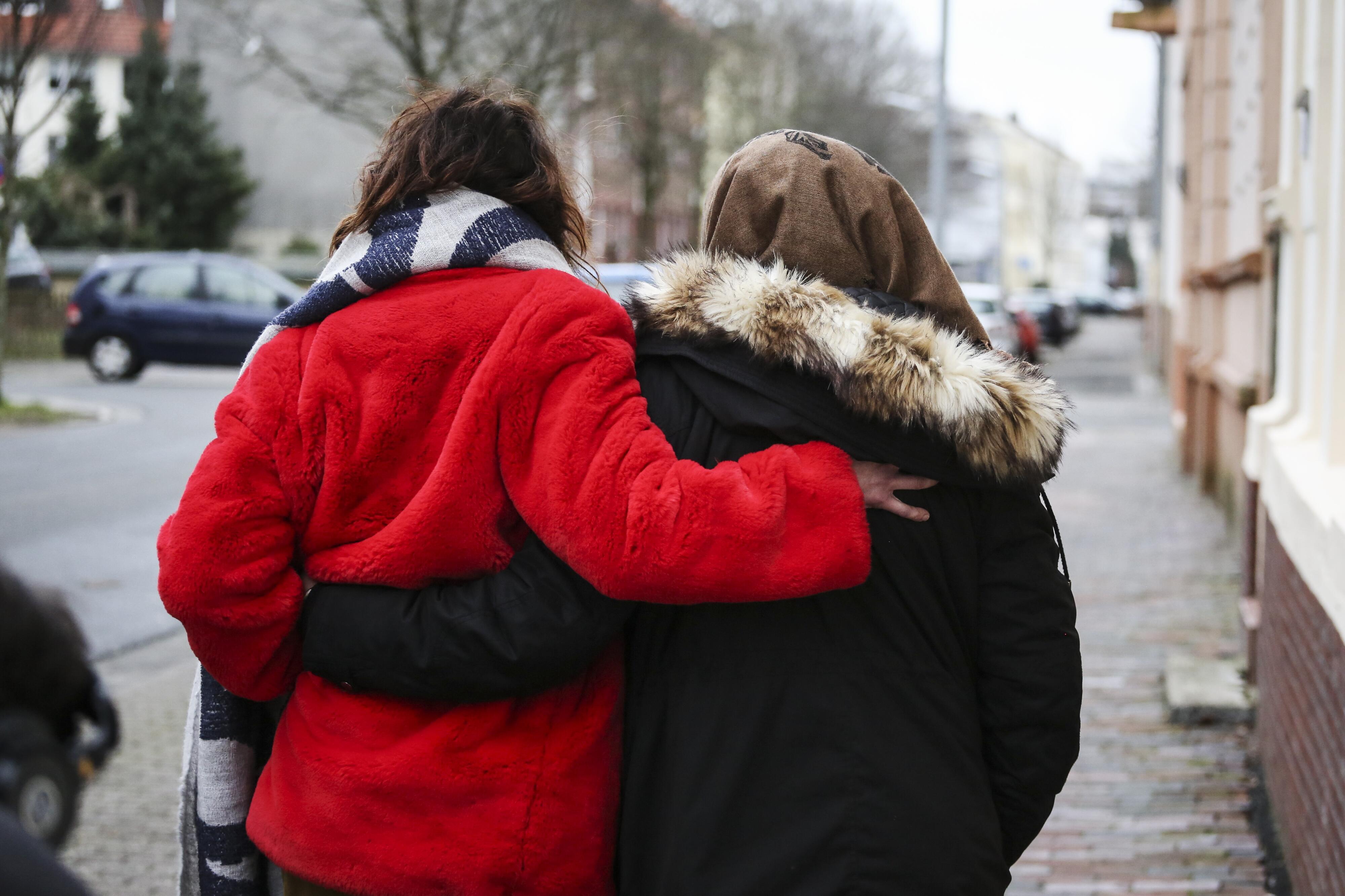 Two women walking down a German road embracing each other