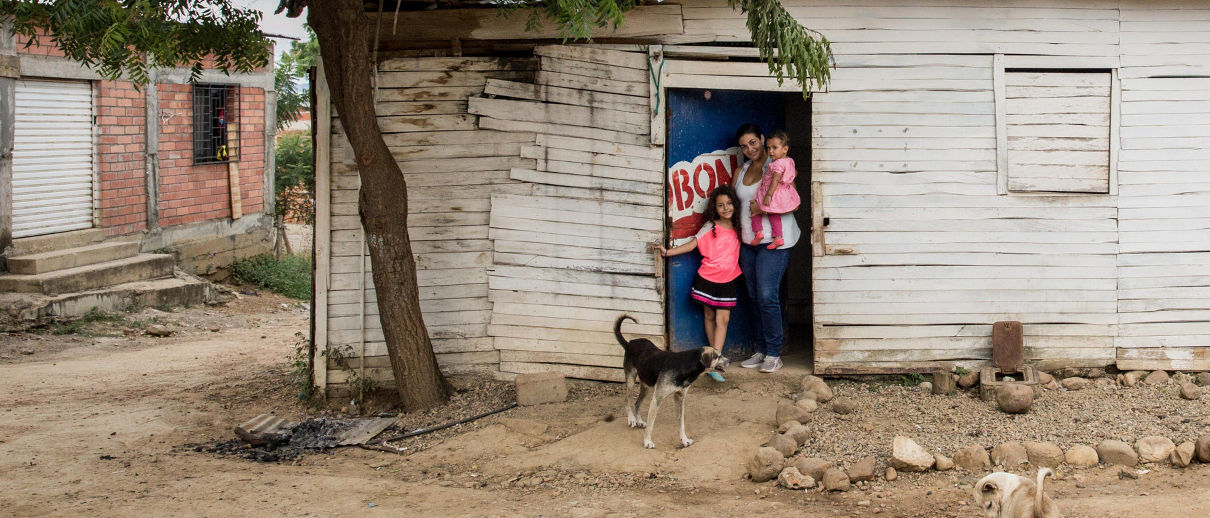 mother with two children and dog in front of her wooden cabin