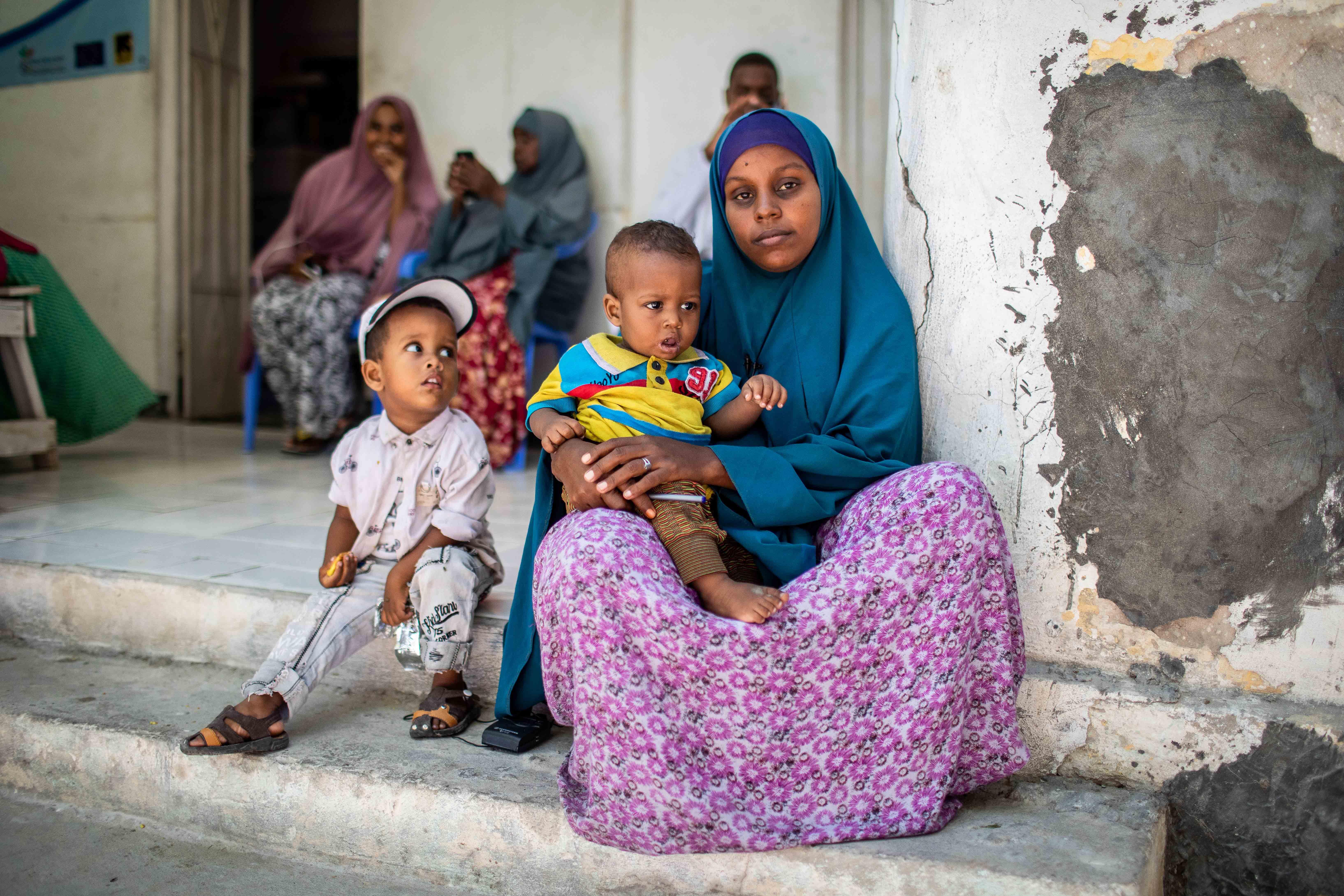 Eine Mutter wartet mit ihren zwei Kindern und weiteren Menschen vor dem Krankenhaus in Karaan, Somalia