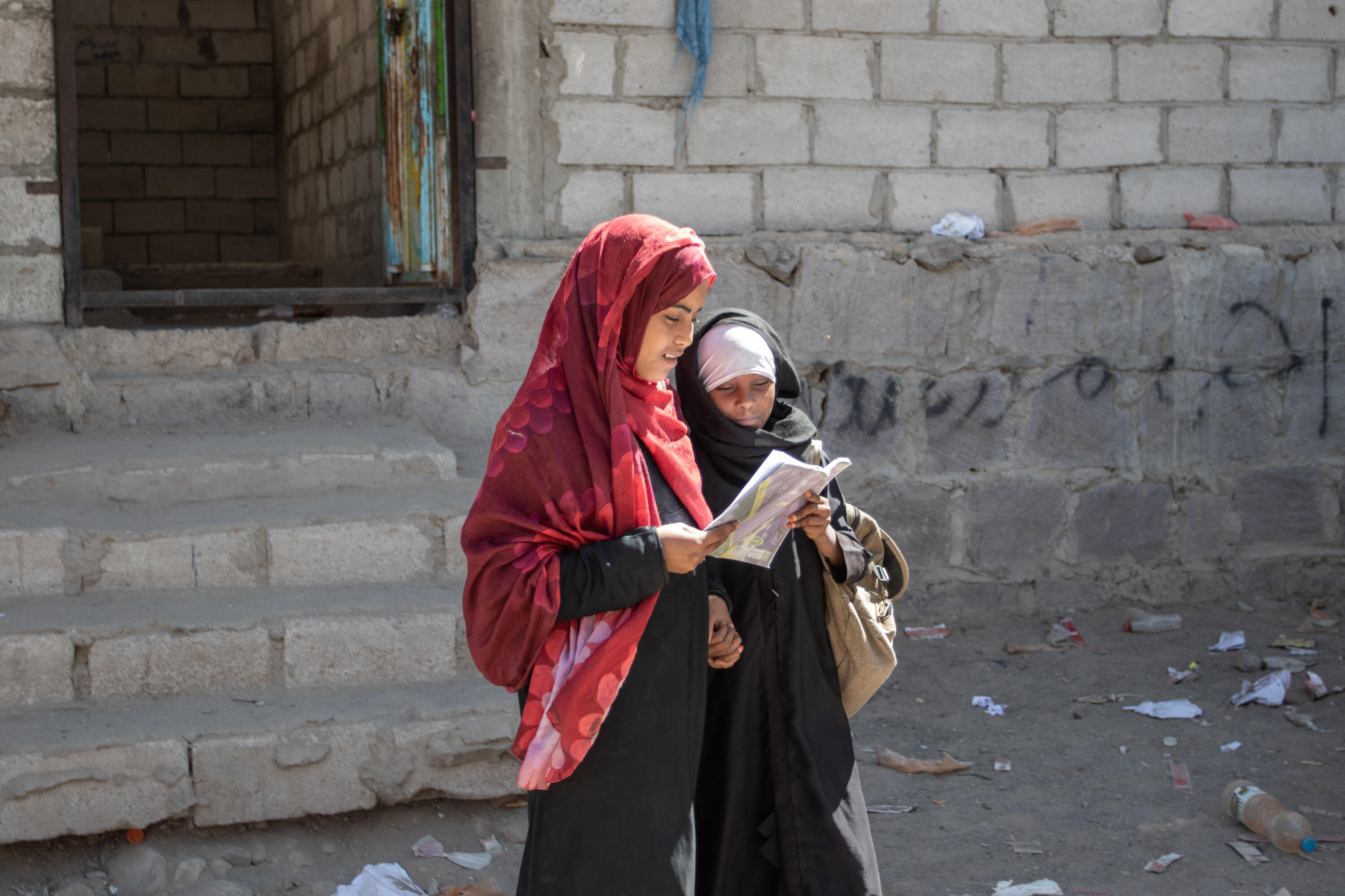 Aisha and Na'aem standing together, reading a book