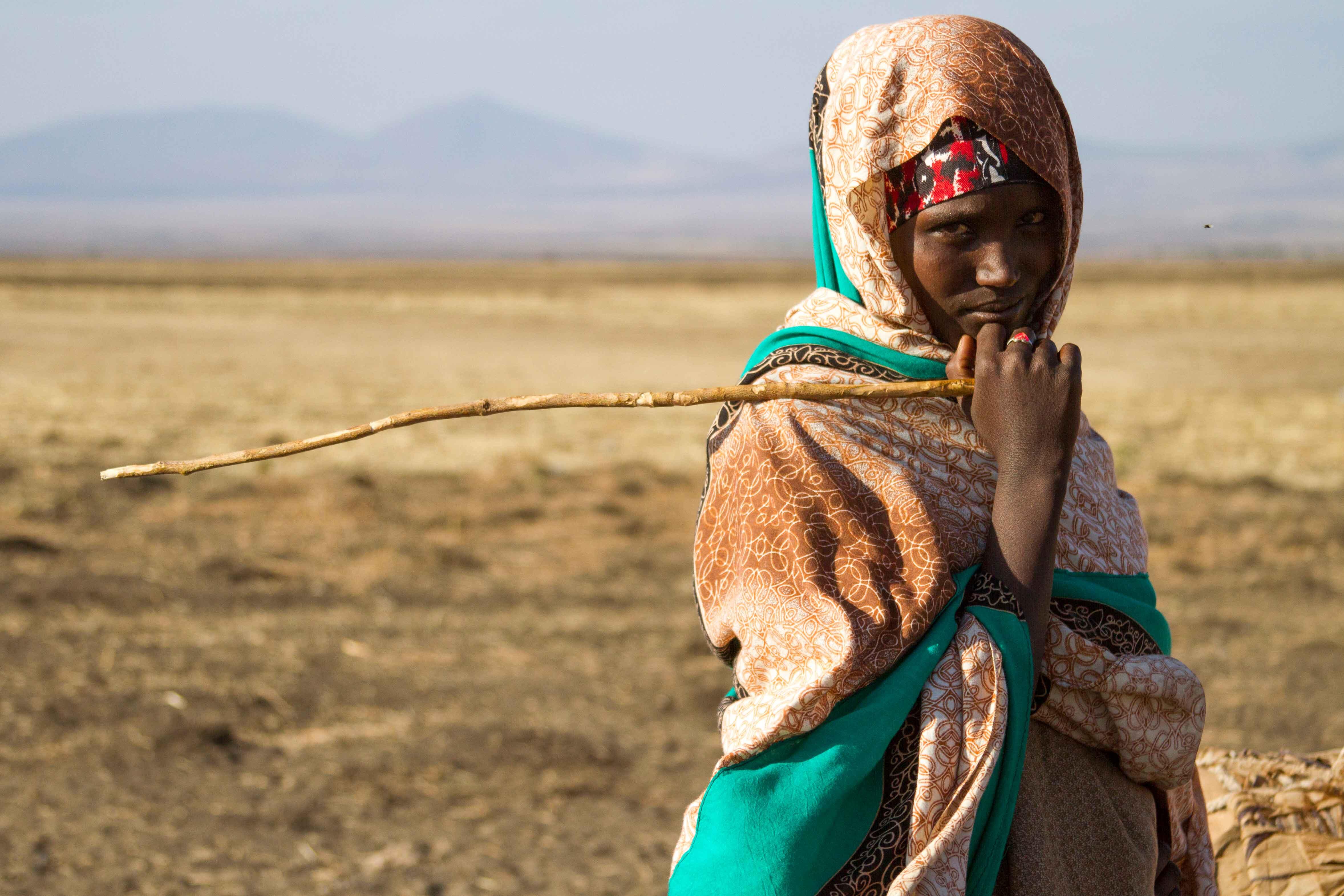 Eine Frau in Äthiopien steht auf einem Feld und schaut in die Kamera.