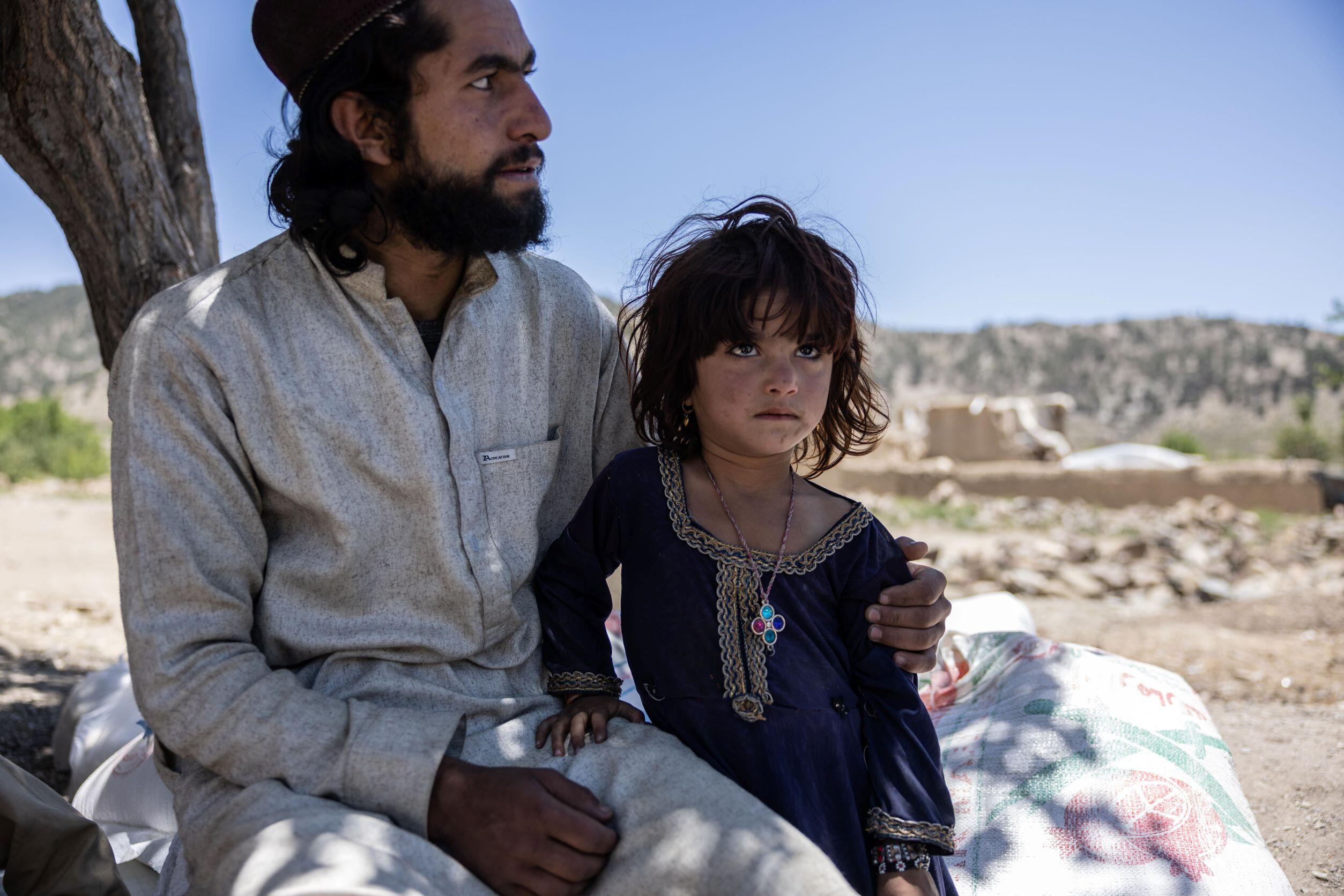 Afghanistan earthquake - An older brother holds his younger sister while looking at the damage to their house