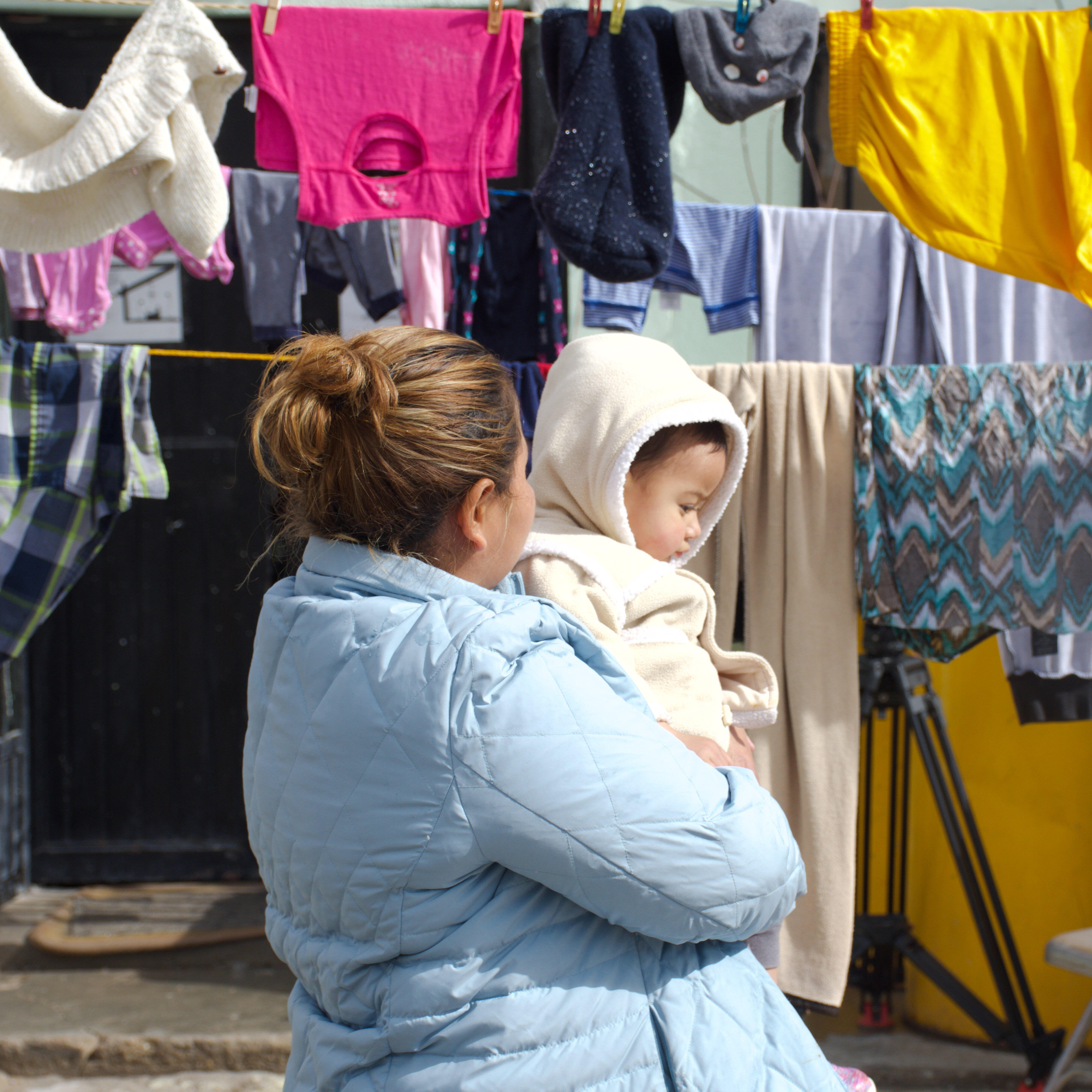 A Guatemalan mother stands holding her baby amid laundry hanging out to dry in Ciudad Juárez, Mexico.